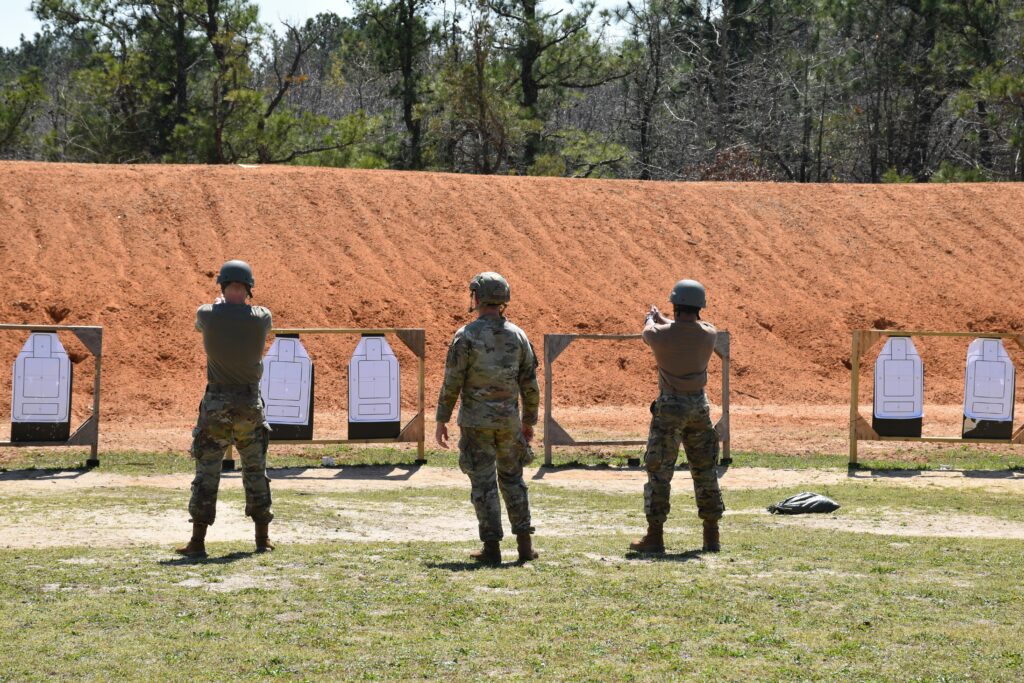 Soldiers engaged in weapons training at an outdoor shooting range.
